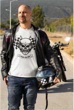 Load image into Gallery viewer, "A man riding a motorcycle wearing a white t-shirt with a skull and checkered flag print."